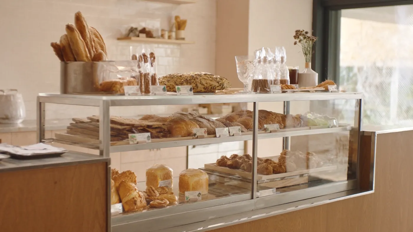 A bakery case full of fresh artisan bread and pastries in warm morning light