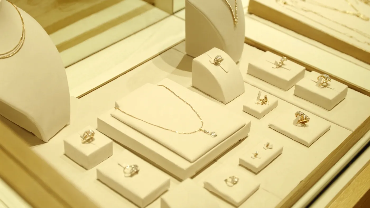 An elegant jewelry display case with fine rings and necklaces under warm light