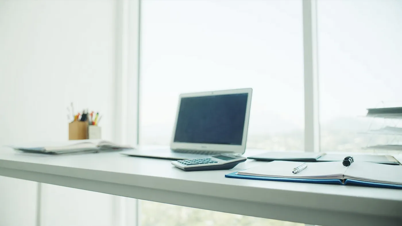 A modern accounting office with a clean desk, laptop, and ledgers