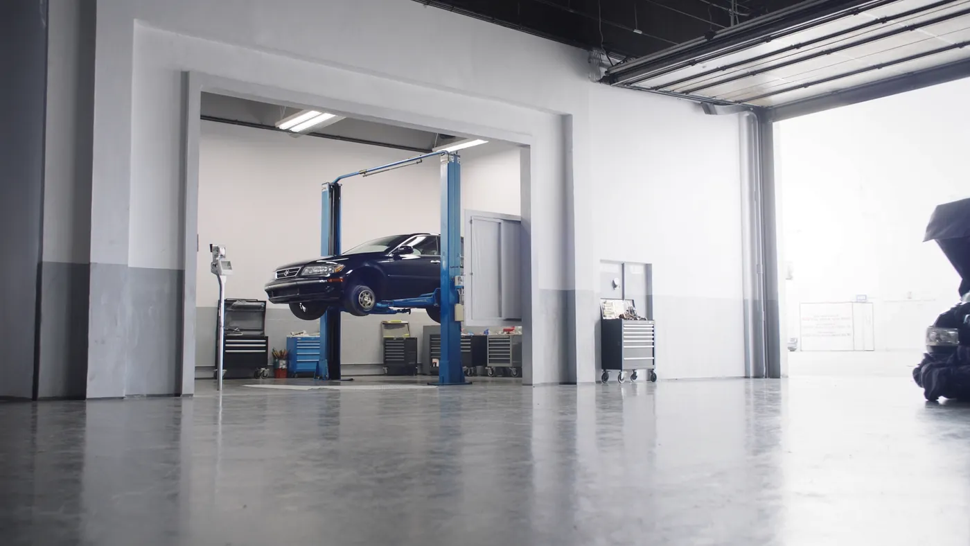A clean modern auto repair bay with a car on a lift and organized tools