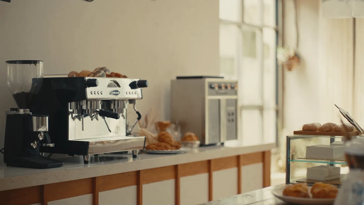 A cozy modern cafe interior with an espresso machine and pastries in morning light