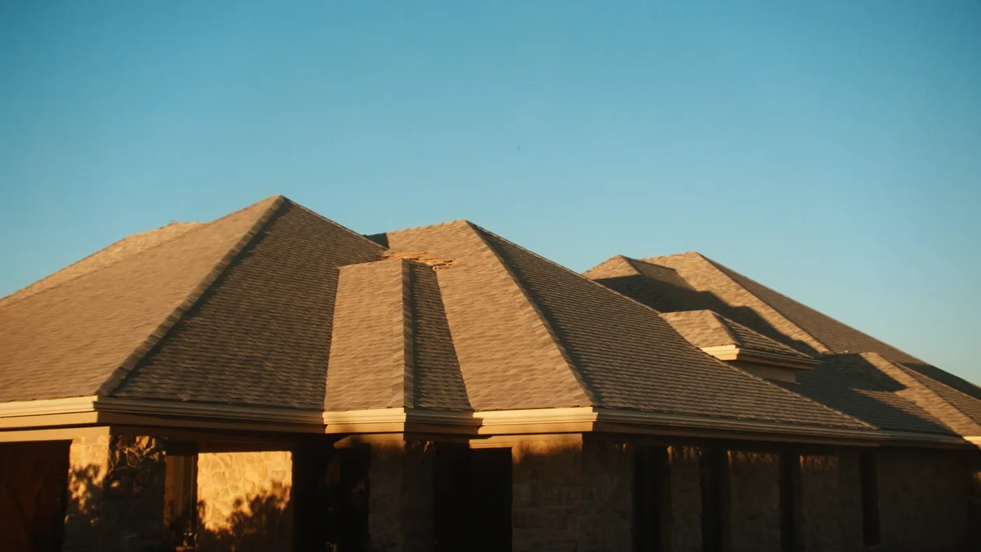A freshly installed architectural shingle roof on a modern home at golden hour