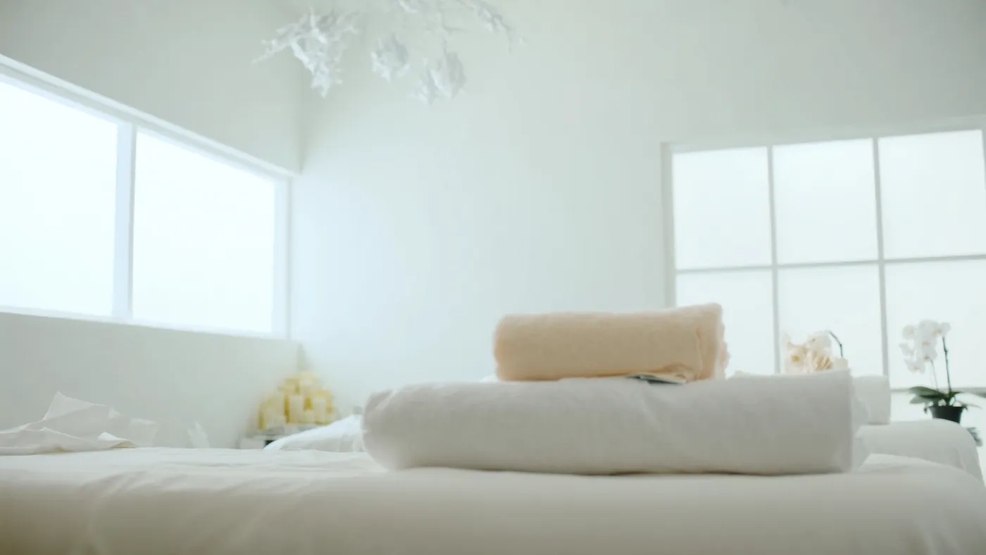 A serene modern spa treatment room with soft towels and candles